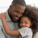 Child Maintenance Trusts. Accompanying image: loving father hugs his daughter with eyes closed