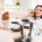 Income protection payment and property settlement. Accompanying image: a female with an injured leg laying on the sofa and talking on the phone.