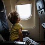 A photo of a little boy looking out of window in an airplane