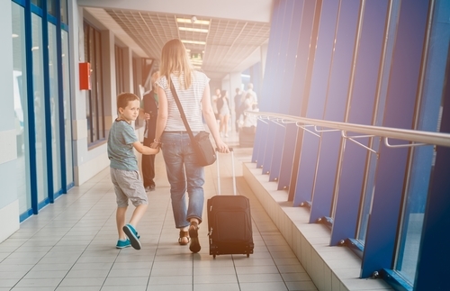A photo of a mother and son with a suitcase at the airport