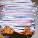 A stock photo of a person carrying a pile of documents and files