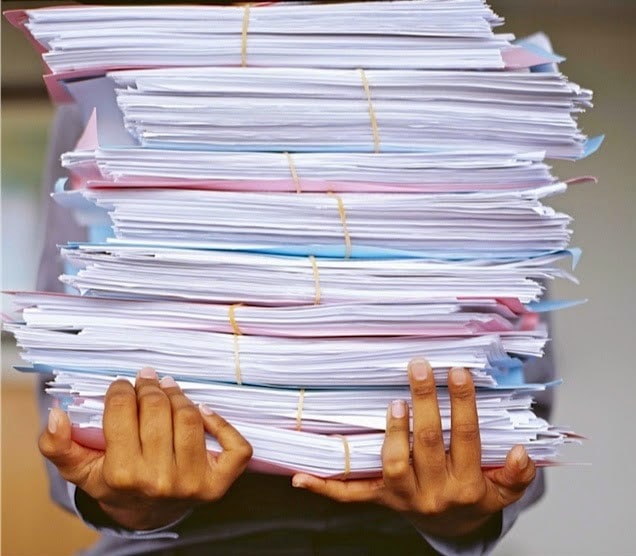A stock photo of a person carrying a pile of documents and files