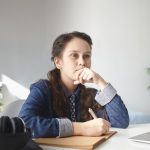 A photo of a school girl sitting at her desk, thinking