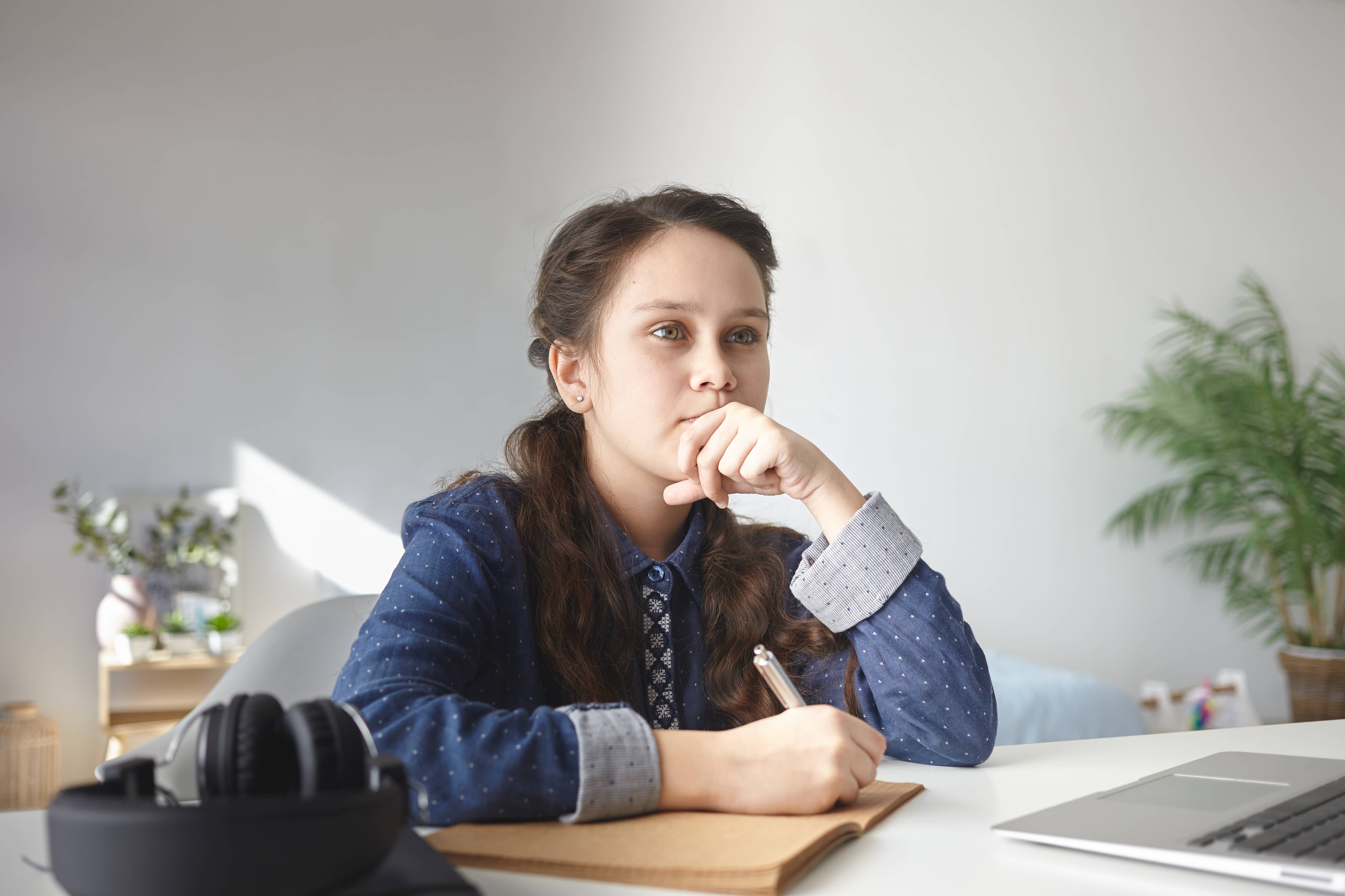 A photo of a school girl sitting at her desk, thinking