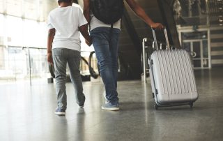 A stock photo of a child holding his father's hand, at the airport.