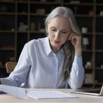 Image of busy elderly freelance business woman doing paperwork, accompanying family law article "Changing a child's surname"