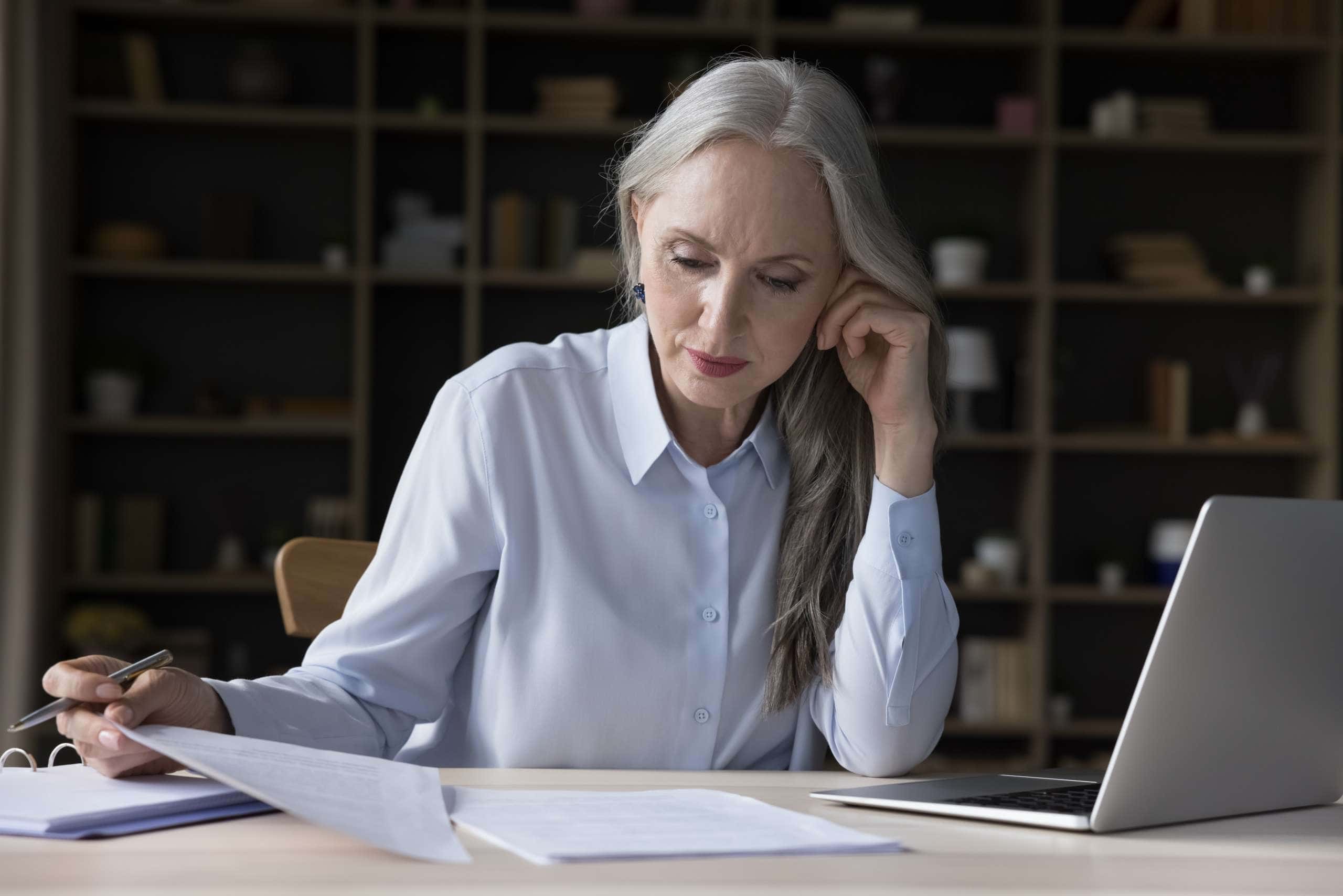 Image of busy elderly freelance business woman doing paperwork, accompanying family law article "Changing a child's surname"