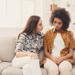 Two sad diverse women talking at home. Female friends supporting each other. Problems, friendship and care concept