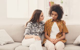 Two sad diverse women talking at home. Female friends supporting each other. Problems, friendship and care concept