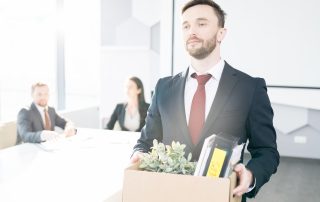 What Happens To Post-Separation Redundancy Payments? Accompanying image: portrait of man holding box of personal belongings leaving office after a redundancy