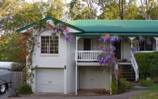 Turbulent times and property settlements. Accompanying picture: Suburban house near Brisbane Australia with wisteria growing over the stairs and porch and tall gum trees behind