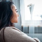 Sad woman sitting on sofa at home and thinking