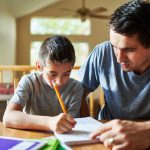 COVID, Courts and Contravention. Accompanying image: father helping son with homework on table at home