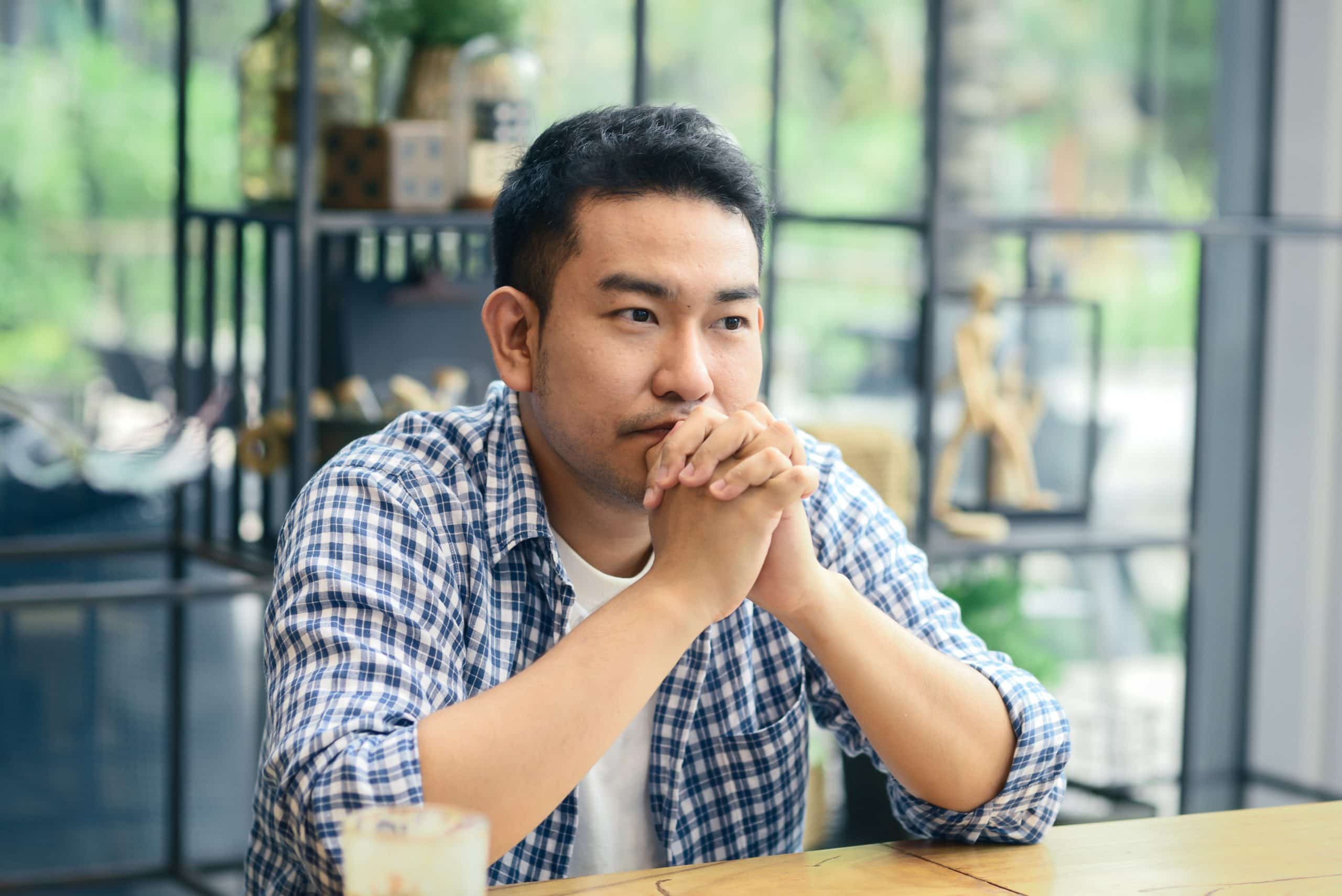 Defacto issues. Accompanying image: a man sitting and thinking in cafe