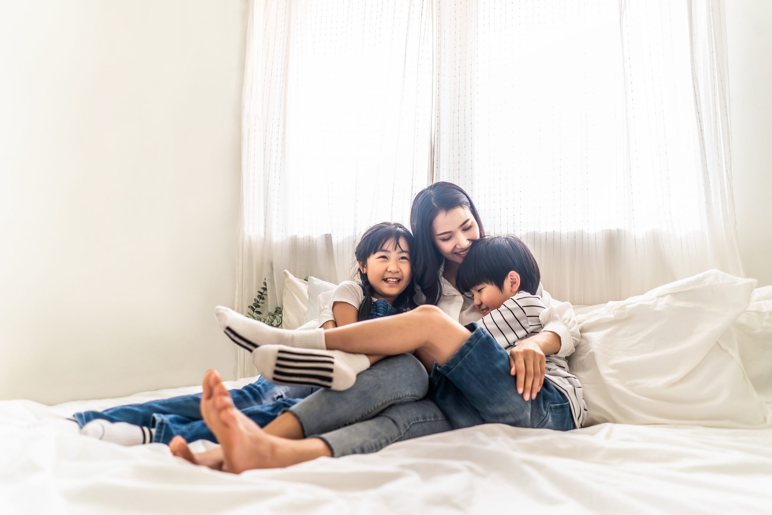 Setting aside a binding child support agreement. Accompanying image: mother, son and daughter sit on bed with happiness and smile in bedroom.