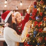 Accompanying image to an article by Michael Lynch Family lawyers. Mother and daughter in Santa hats putting decorations on xmas tree, festive kitchen interior