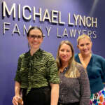 Photo of Susan Miranda, Zoe Adams and Stephanie Brown in front of the Michael Lynch Family Lawyers sign