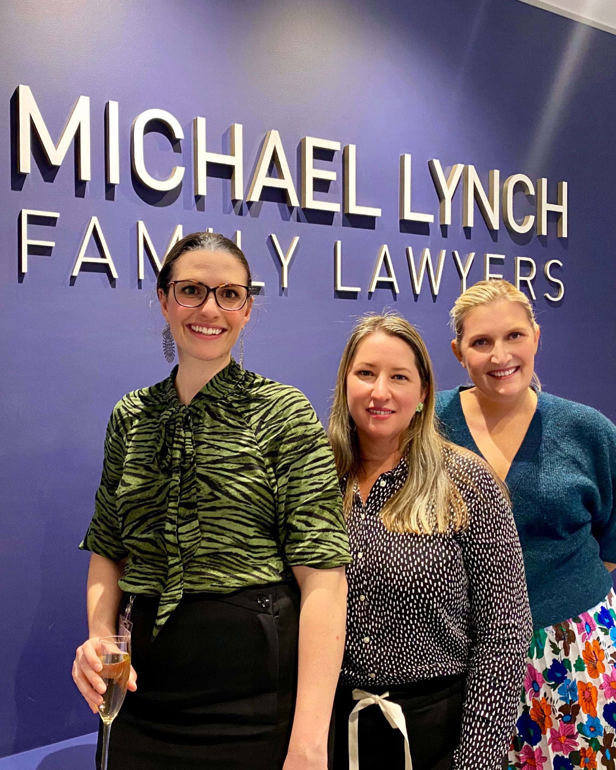 Photo of Susan Miranda, Zoe Adams and Stephanie Brown in front of the Michael Lynch Family Lawyers sign