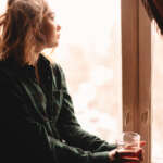 Image of a woman drinking tea and looking through window
