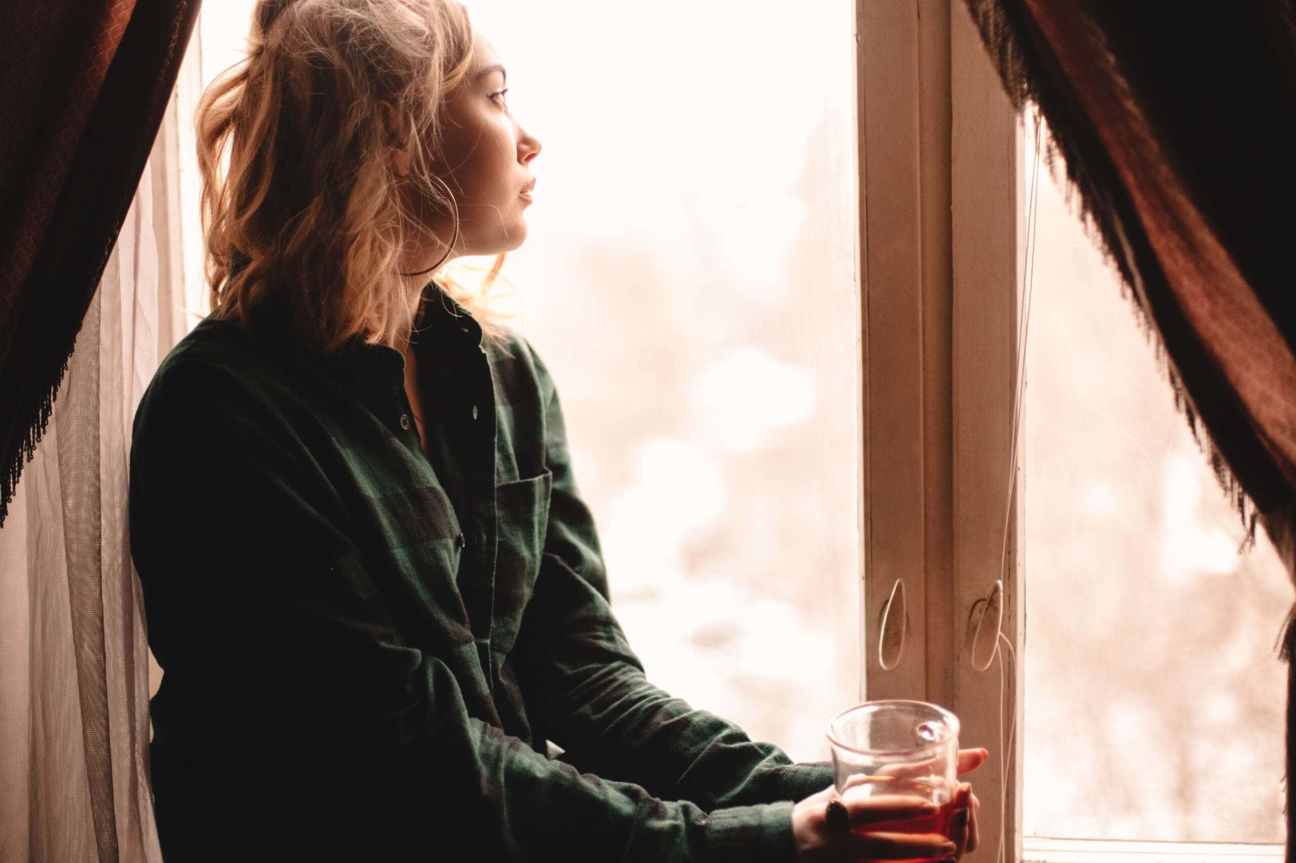 Image of a woman drinking tea and looking through window
