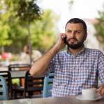 Image of a man using phone in cafe, accompanying family law article "Do’s and don’ts on accessing your ex’s financial documents"