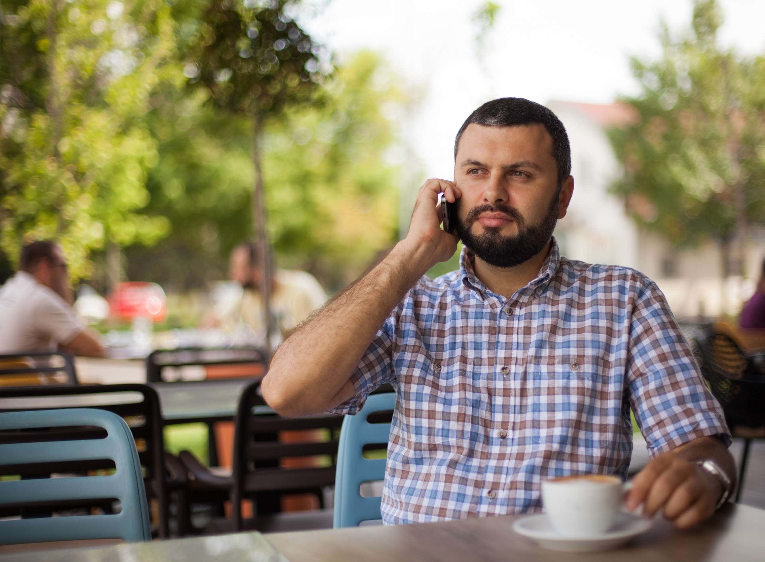 Image of a man using phone in cafe, accompanying family law article "Do’s and don’ts on accessing your ex’s financial documents"