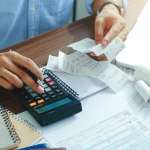 Image of a person using a calculator, accompanying family law article "Dealing with capital gains tax in a property settlement"