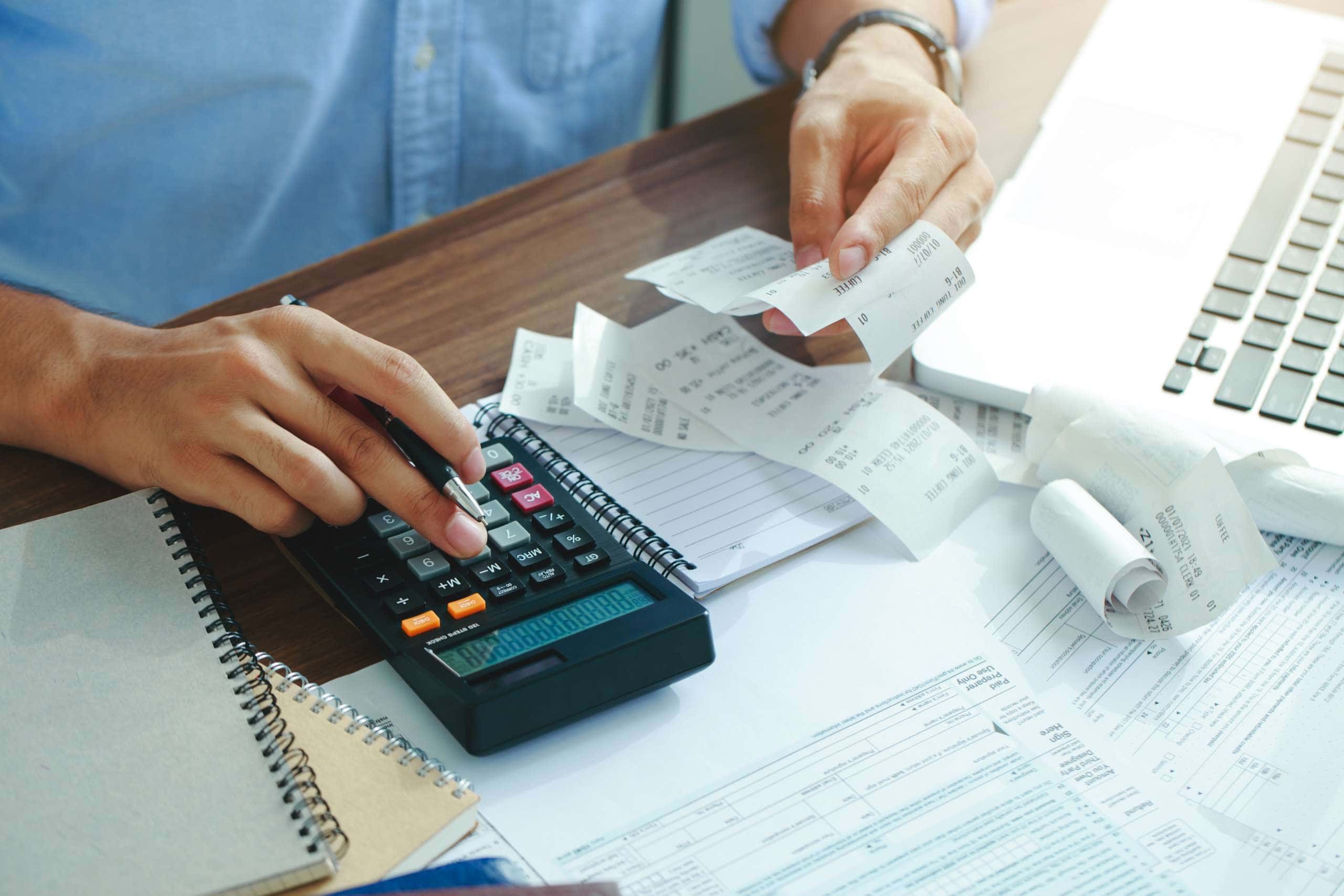 Image of a person using a calculator, accompanying family law article "Dealing with capital gains tax in a property settlement"