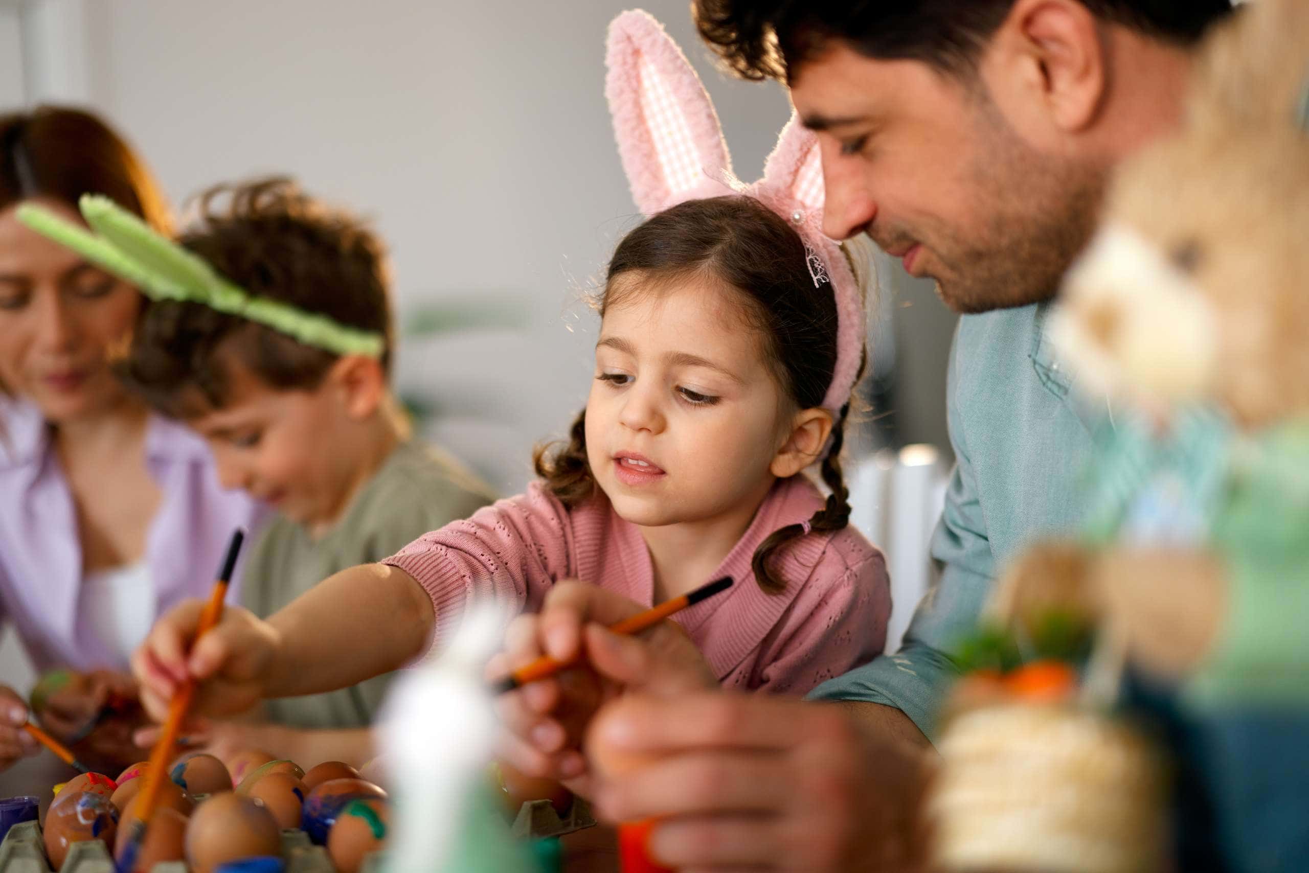 Little girl painting easter eggs with father during family celebration